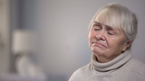 Crying old lady sitting alone in living room, life and health problems, close-up - Фото, зображення