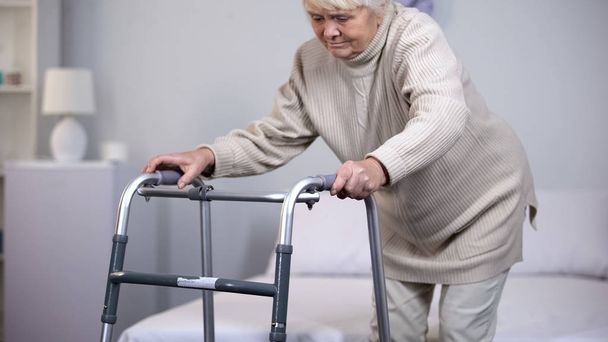 Elderly woman with walking frame, medical equipment using after trauma, hospital - Fotó, kép