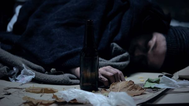 Drunk person sleeping on cold urban street at night, alcohol abuse and addiction - Фото, зображення