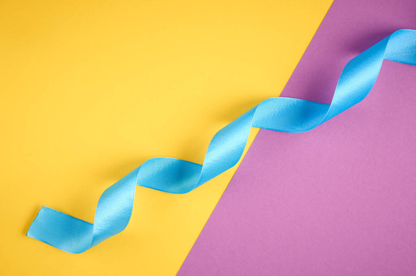 Blue ribbon on purple and yellow background composition, flat lay - Foto, immagini