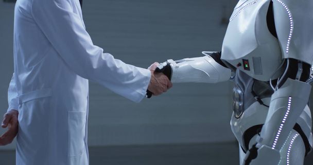 Человек и робот пожимают друг другу руки - Фото, изображение