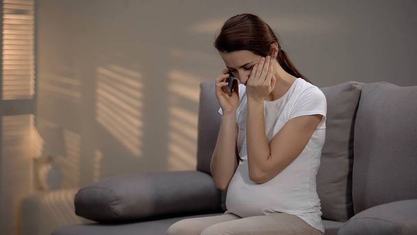 Crying pregnant lady talking on phone, receiving bad news, depression and sorrow - Fotó, kép