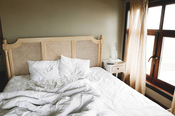 Cama com lençóis brancos e mesa de cabeceira vintage com decoração no windo
 - Foto, Imagem