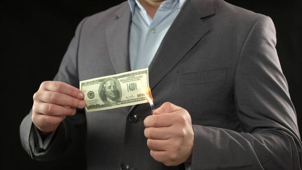 One hundred dollar bill on fire, male going bankrupt, losing money, inflation - Foto, Imagen