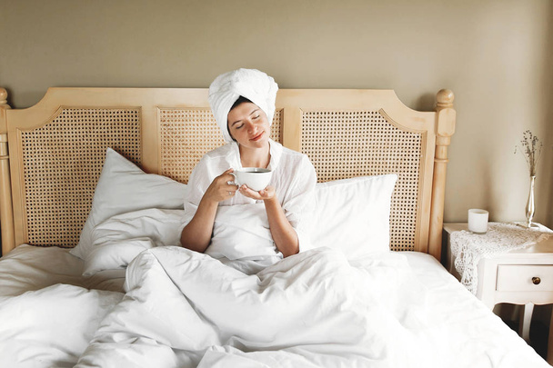 Bella felice giovane donna che beve caffè a letto in camera d'albergo
 - Foto, immagini