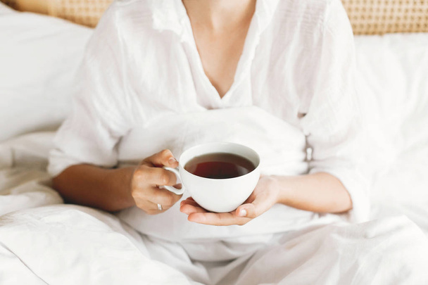 Biały kubek z kawą lub herbatą w rękach dziewcząt zbliżenie. Piękny h - Zdjęcie, obraz