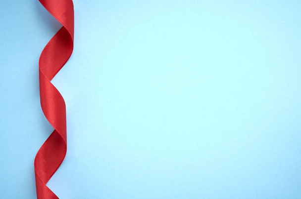 Red ribbon on blue background composition, flat lay - Photo, Image