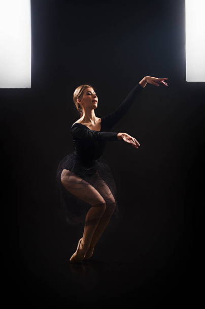 Charming girl ballerina in a black suit, is dancing a ballet in the light of the contour . - 写真・画像