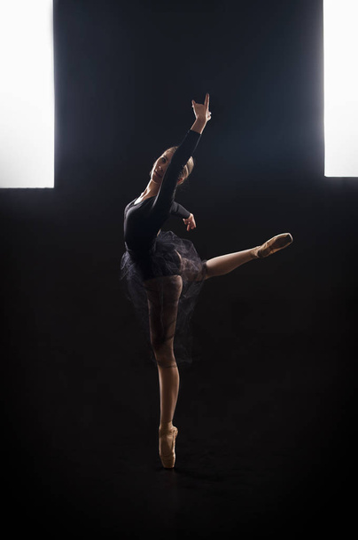 Charming girl ballerina in a black suit, is dancing a ballet in the light of the contour . - Zdjęcie, obraz