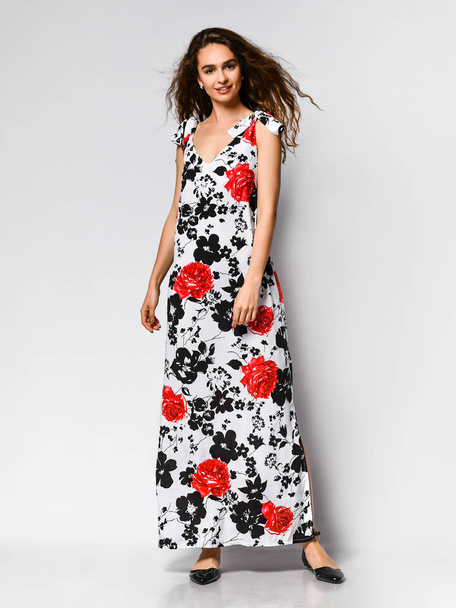 Young beautiful woman posing in new red flower pattern fashion dress on white background. Fashion spring summer photo - 写真・画像