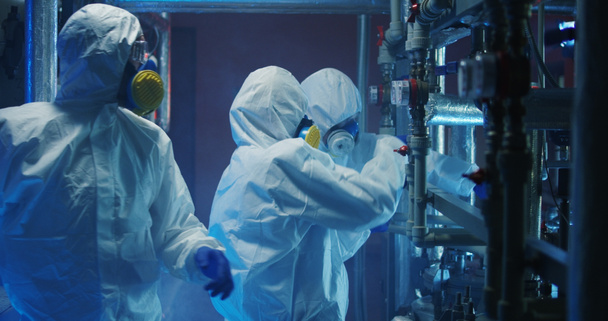 Scientists in hazmat suits checking equipment - Photo, Image