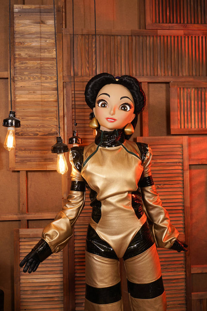 schönes Mädchen mit Gesichtsmaske Puppe in Leder Space Jumpsuit posiert in ihrem Zimmer mit Glühbirnen allein - Foto, Bild