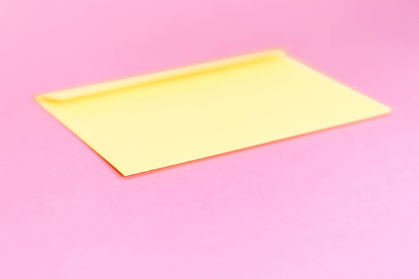 Schoonheid gele envelop; branding mock up; Vooraanzicht op pastel roze achtergrond. - Foto, afbeelding