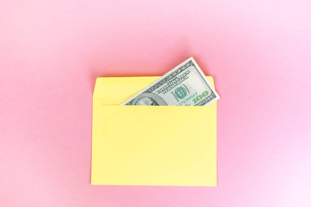 El primer plano del dinero en sobres amarillos yace sobre el fondo rosa pastel. Marca maqueta hacia arriba; vista frontal sobre fondo rosa
.  - Foto, imagen