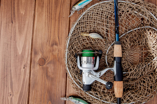 Aparejos de pesca - spinning de pesca, anzuelos y señuelos en bac de madera
 - Foto, Imagen