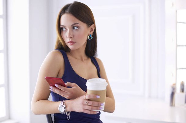 Nuori nainen kahvilassa juo kahvia ja puhuu matkapuhelimella - Valokuva, kuva