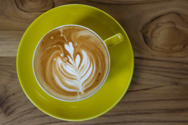 Cappuccino coffee. Yellow cup on wooden table. - Фото, зображення