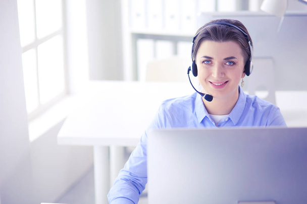 Serious pretty young woman working as support phone operator with headset in office - Foto, Imagen
