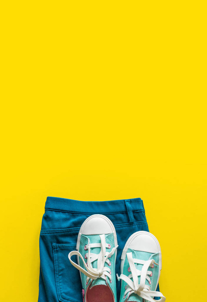 New turquoise sneakers on yellow background with copy space. - Photo, image