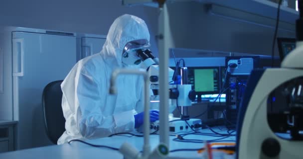 Naukowiec badając próbkę za pomocą mikroskopu - Materiał filmowy, wideo