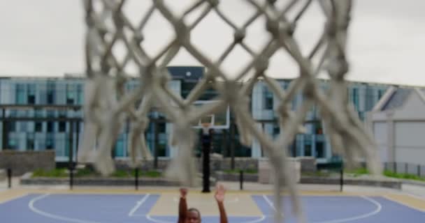 High angle view of African american basketball player playing basketball in basketball court. Close-up of basketball hoop 4k - Záběry, video