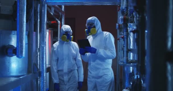 Científicos en trajes de materiales peligrosos que realizan trabajos de mantenimiento
 - Imágenes, Vídeo