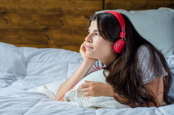 Νεαρή γυναίκα απολαμβάνοντας μουσική στο κρεβάτι. - Φωτογραφία, εικόνα