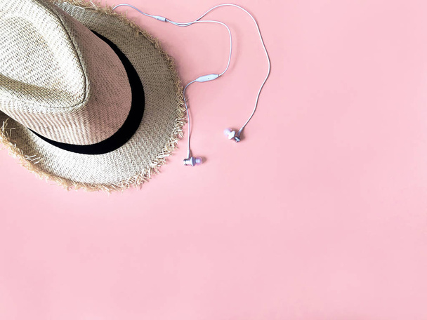 Woven hat and white ear phone on pastel pink color background su - Φωτογραφία, εικόνα