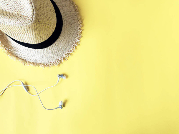Woven hat and white ear phone on pastel yellow color background  - Photo, Image