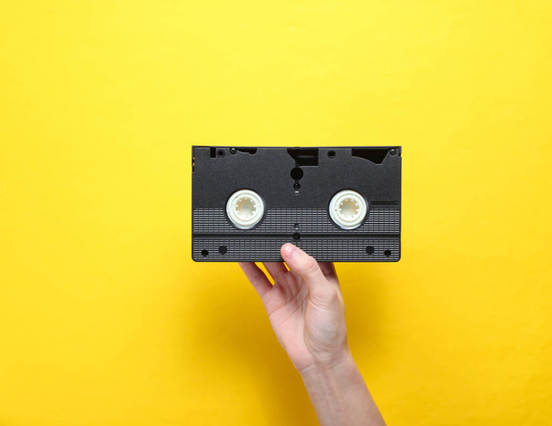 Kobiece uchwyty kasety wideo na żółtym tle. Styl retro, Popkultura, minimalizm, widok z góry - Zdjęcie, obraz