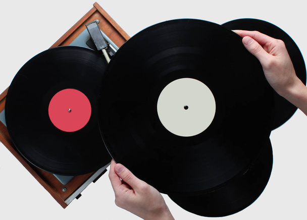 Woman hands holding vinyl record, vinyl player with records on white background. Retro style, 80s, top view - Photo, Image