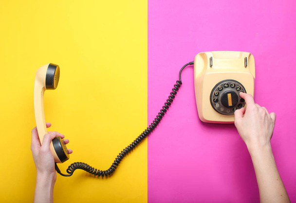 Mujer recoge el número del teléfono giratorio y sostiene el auricular sobre un fondo de papel de color. Vista superior, minimalismo
 - Foto, imagen