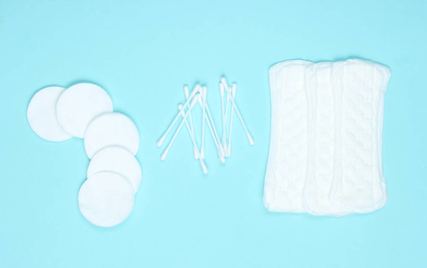 Hygiene products on blue pastel background. Cotton pads, women's pads, cotton ear sticks. Top view, flat la - Foto, Imagem