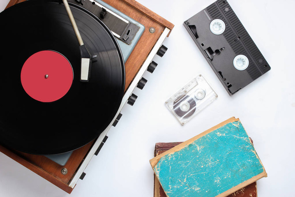 Pop kultura retro objekty na bílém pozadí. Vinylový přehrávač, staré knihy, audio, videokazety. Top view, media, flat lay - Fotografie, Obrázek