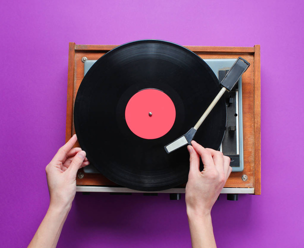 女性の手は紫の背景にプレートとレトロビニールレコードプレーヤーを設定します。トップ表示 - 写真・画像