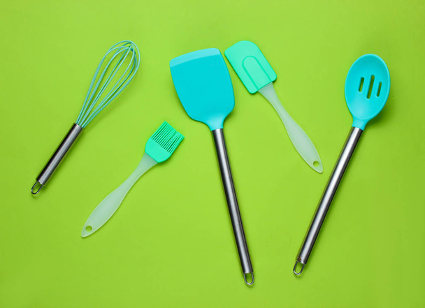 Outils en silicone avec poignées métalliques pour cuisiner sur fond vert
 - Photo, image