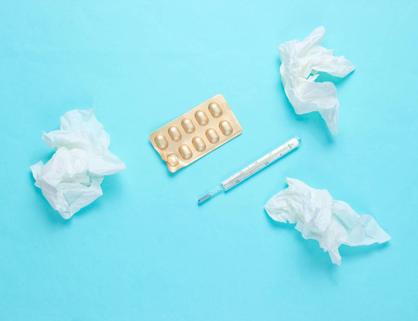 The concept of treating cold diseases. Used nasal wipes, thermometer, pills on blue background. Top view - Φωτογραφία, εικόνα