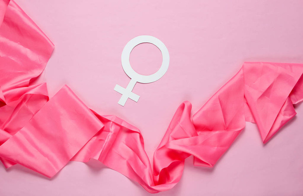 Vrouwelijke gender symbool, satijnen lint op pastel roze achtergrond. Minimalisme. Top View - Foto, afbeelding