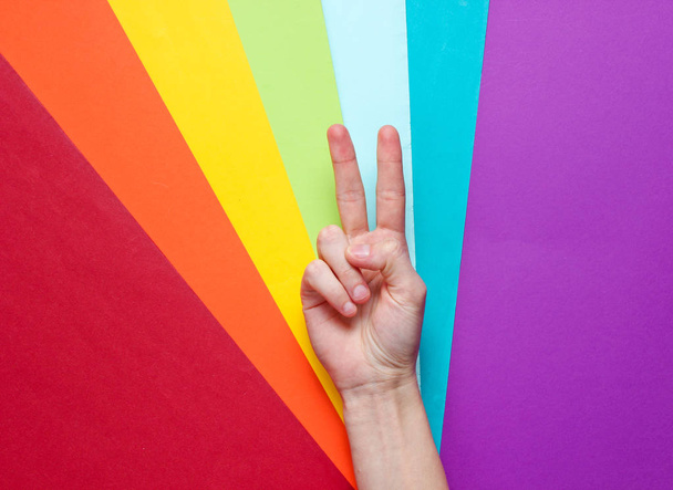 lgbt-Konzept. Minderheitensex. Hand mit Friedenszeichen auf Regenbogenhintergrund. Draufsicht, Minimalismus - Foto, Bild