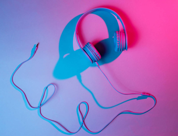 Headphones with cable. Retro wave, blue red neon light, ultraviolet. Top view, minimalism - Photo, Image