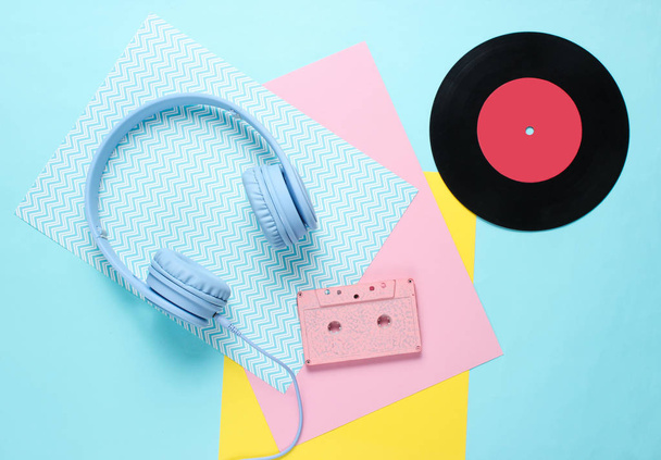 Fülhallgató és fülhallgató hangkazettákkal színes papírhátterű. Retro stílus, minimalizmus. Lapos fekvés. Felülnézet. - Fotó, kép