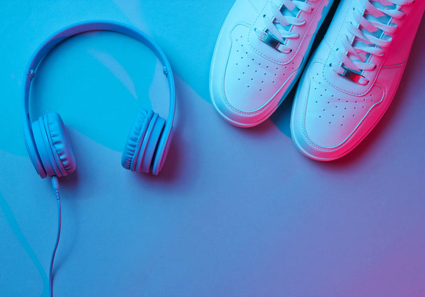 Sneakers with wireless headphones. Retro wave, neon light, ultraviolet. Top view, minimalism - Photo, Image