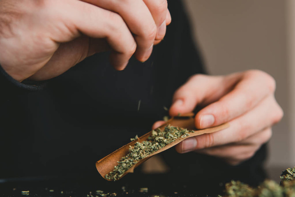 Close up marijuana joint with lighter. Man rolling a marijuana weed blunt. Man rolling marijuana cannabis blunt. - Fotografie, Obrázek