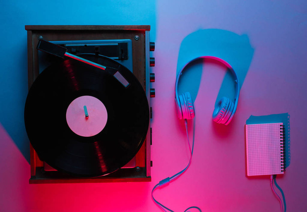Lecteur vinyle avec disque lp, écouteurs. Une boîte de nuit. Onde rétro, néon rouge bleu, ultraviolet. Vue d'en haut, minimalisme - Photo, image