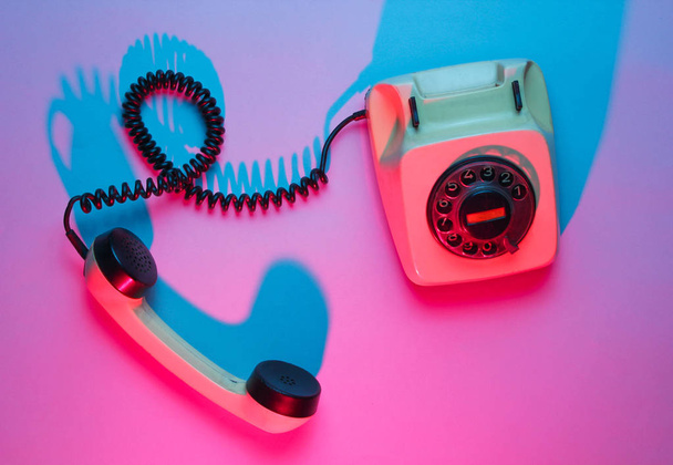 Vintage rotary phone. Retro wave, pink blue neon light, ultraviolet. Top view, minimalism - Photo, Image
