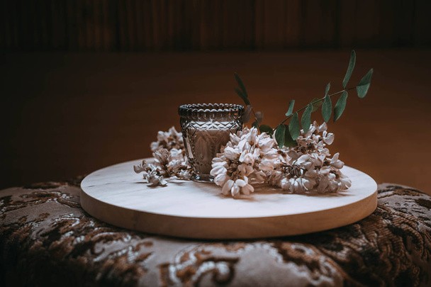 ветка жасмина на деревянной тарелке рядом со свечой
 - Фото, изображение