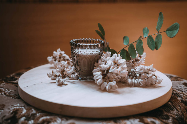 ветка жасмина на деревянной тарелке рядом со свечой
 - Фото, изображение