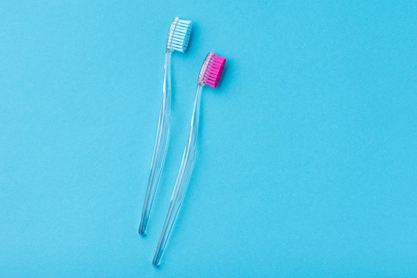 青い背景に2つのプラスチックカラフルな歯ブラシ、クローズアップ - 写真・画像