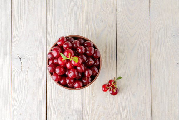 ripe cherries in a bowl on a textured wooden background - Fotografie, Obrázek