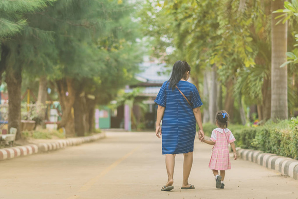 Maman et fille élève fille tenant la main dans la rue aller à la salle de classe ensemble
. - Photo, image